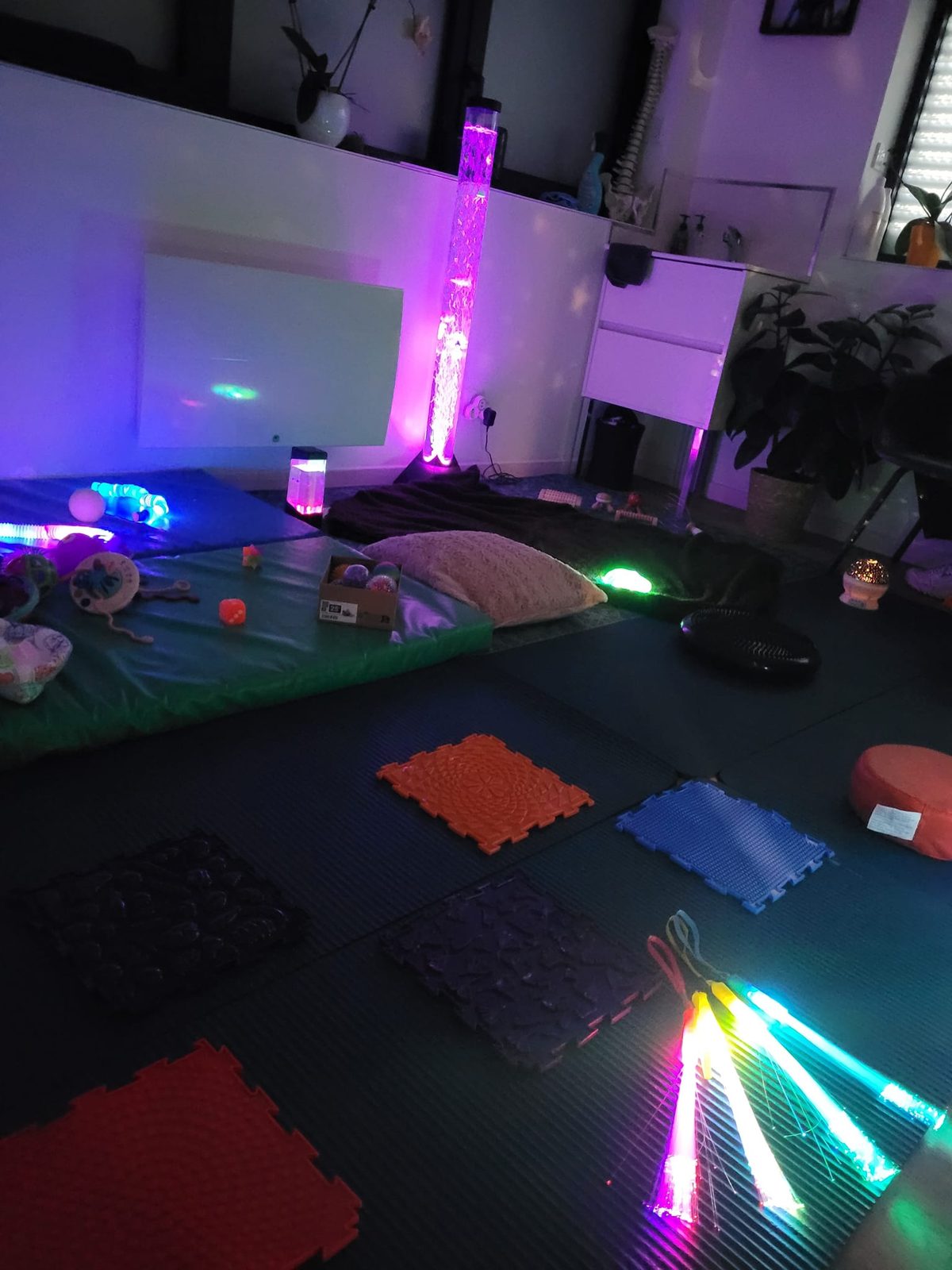 La salle Snoezelen d'Anaïs : colonne à bulles violette, tapis sensoriels et fibres optiques lumineuses